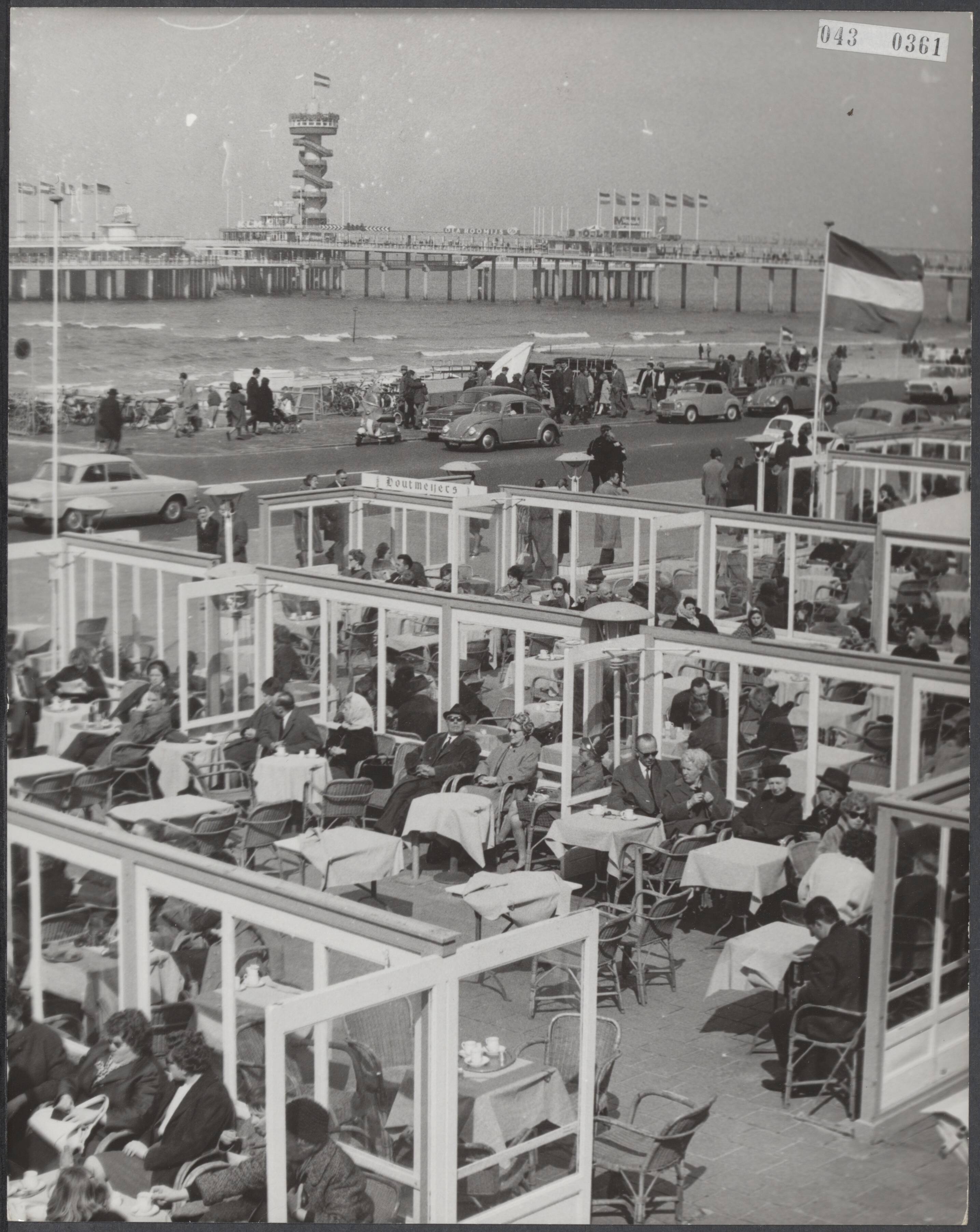 Fotocollectie Elsevier Binnenland — Scheveningen had het druk met zijn wandelaars, fietsers, auto's en andere zeebezoeker. Volle terrasjes [in de achtergrond de Pier] — Foto: Nijs, Jac. de / Anefo. Licentie: Set B: Rechtenvrij / Publiek Domein. Bron: Nationaal Archief. http://hdl.handle.net/10648/adf8c64e-d0b4-102d-bcf8-003048976d84