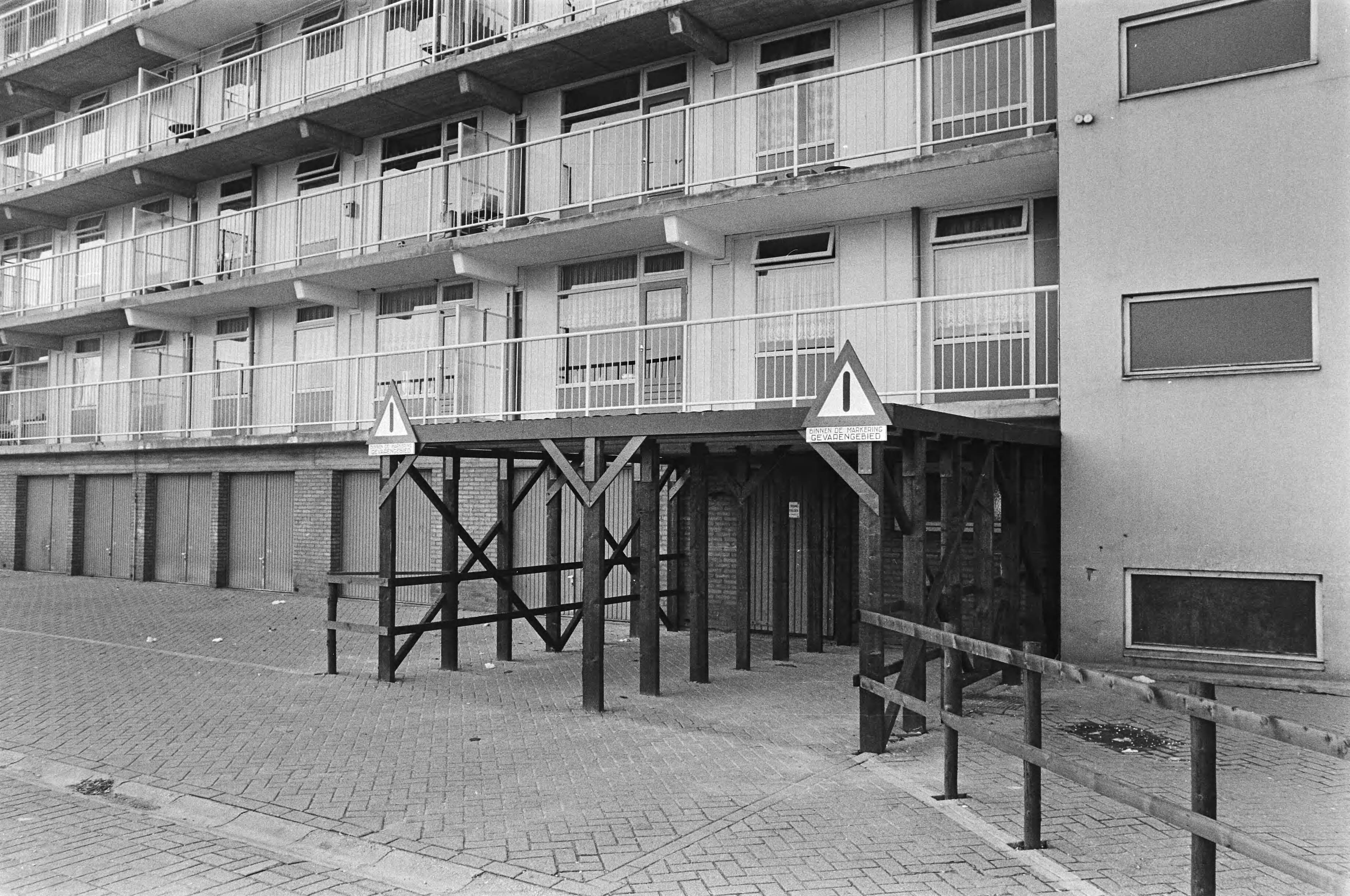 Fotocollectie Anefo — Flats in Limburgse Eygelshoven moet worden gesloopt wegen gebruik ondeugdelijk materiaal; houten tunnel ter beveiliging bewoners — Foto: Verhoeff, Bert / Anefo. Licentie: Set B: Rechtenvrij / Publiek Domein. Bron: Nationaal Archief. http://hdl.handle.net/10648/ac916af4-d0b4-102d-bcf8-003048976d84