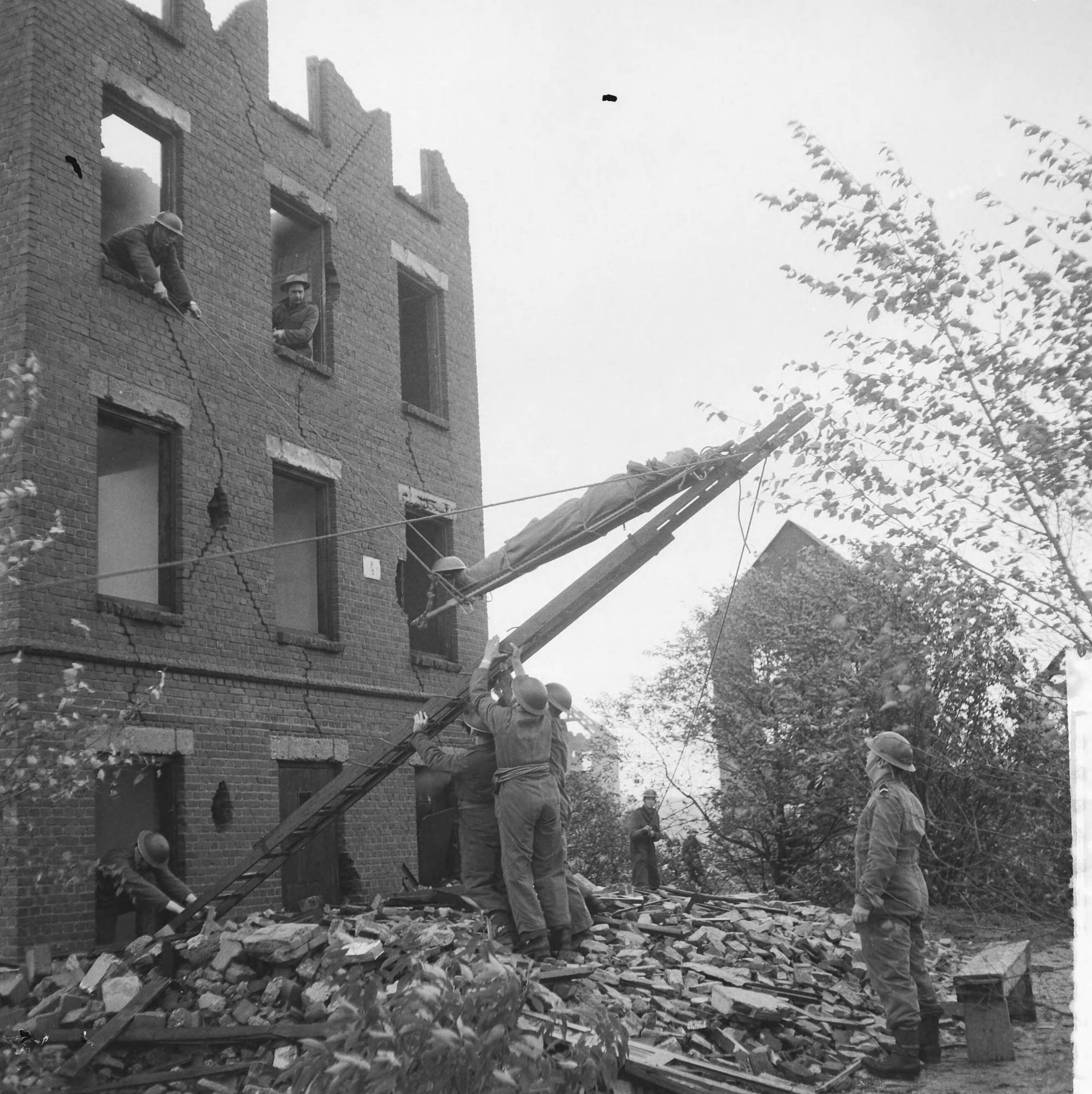 Fotocollectie Anefo — Oefening Korps Mobiele Colonnes in kamp Crailo bij Laren (N.H.), redding van gewonden uit huizen (opdracht Trouw) — Foto: Lindeboom, Henk / Anefo. Licentie: Set B: Rechtenvrij / Publiek Domein. Bron: Nationaal Archief. http://hdl.handle.net/10648/a9bdc192-d0b4-102d-bcf8-003048976d84
