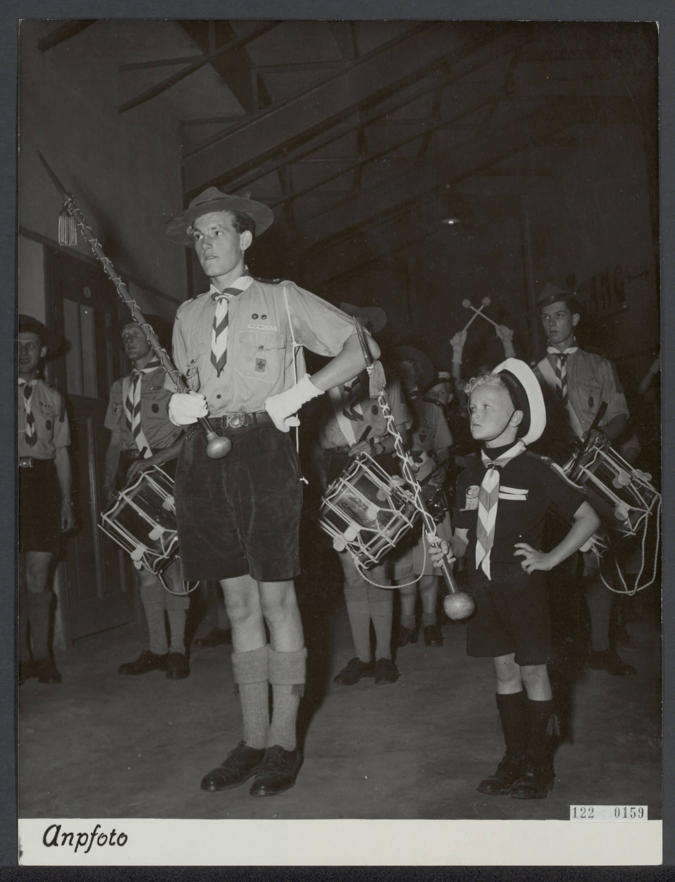 Padvinderij — Padvinders Mars-Bandconcours te Den Haag. In het Circusgebouw is zaterdag het derde Nationale Padvinders en Padvindsters mars-bandconcours gehouden waaraan door twintig drumbands uit het gehele land werd deelgenomen. De foto toont de grootste en de kleinste tamboer-majoor in actie — Foto: ANP / RVD of rechtenvrij. Licentie: Set B: Rechtenvrij / Publiek Domein. Bron: Nationaal Archief. http://hdl.handle.net/10648/af28c898-d0b4-102d-bcf8-003048976d84