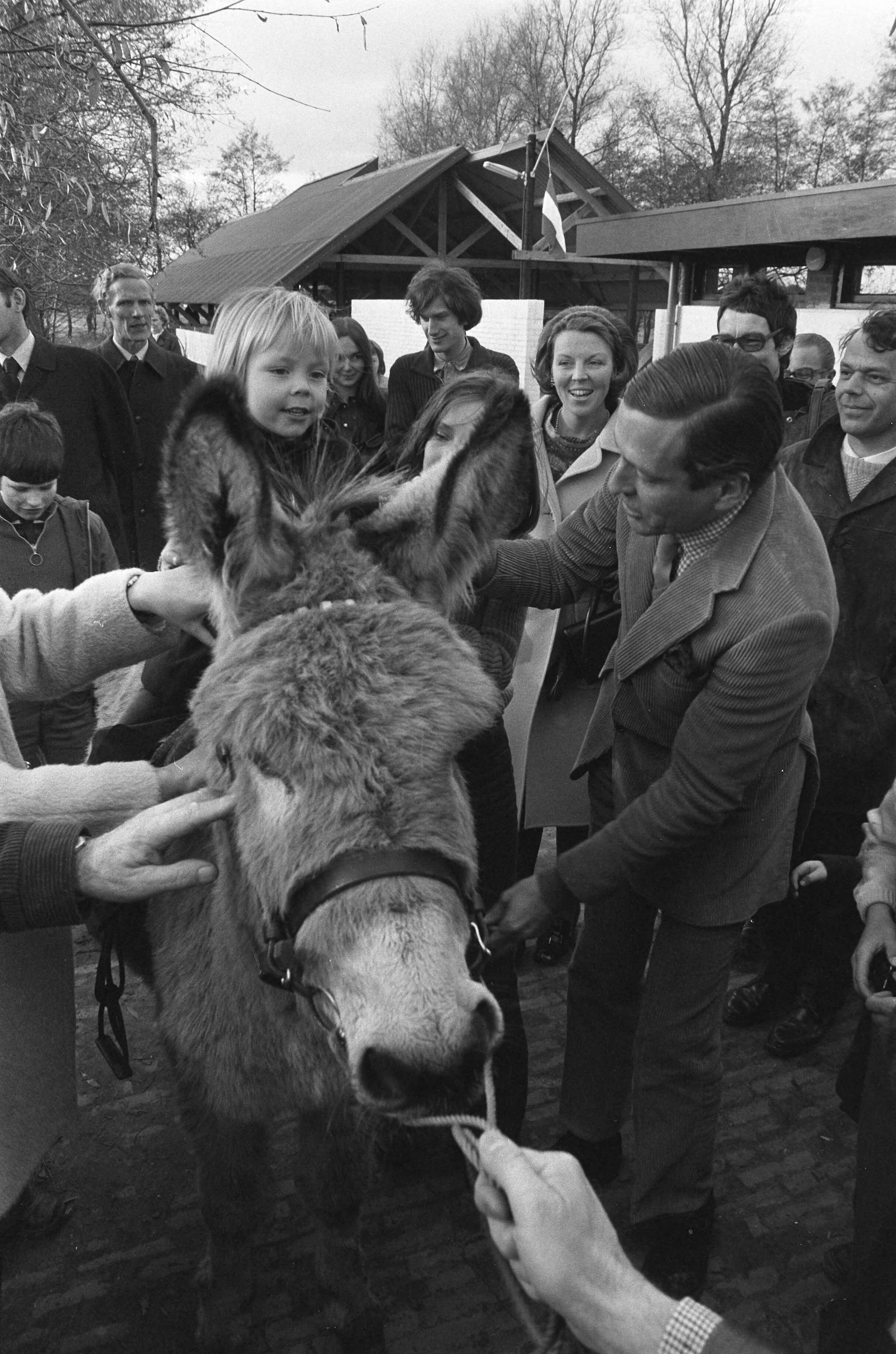 Prinses Beatrix en Prins Claus met hun kinderen bij de opening van kinderboerderij "De Vrije Teugel" in Soest — Prins Claus zet Constantijn op een ezel, op de achtergrond prinses Beatrix — Foto: Fotograaf Onbekend / Anefo. Licentie: Set B: Rechtenvrij / Publiek Domein. Bron: Nationaal Archief. http://hdl.handle.net/10648/ac3ca5fa-d0b4-102d-bcf8-003048976d84