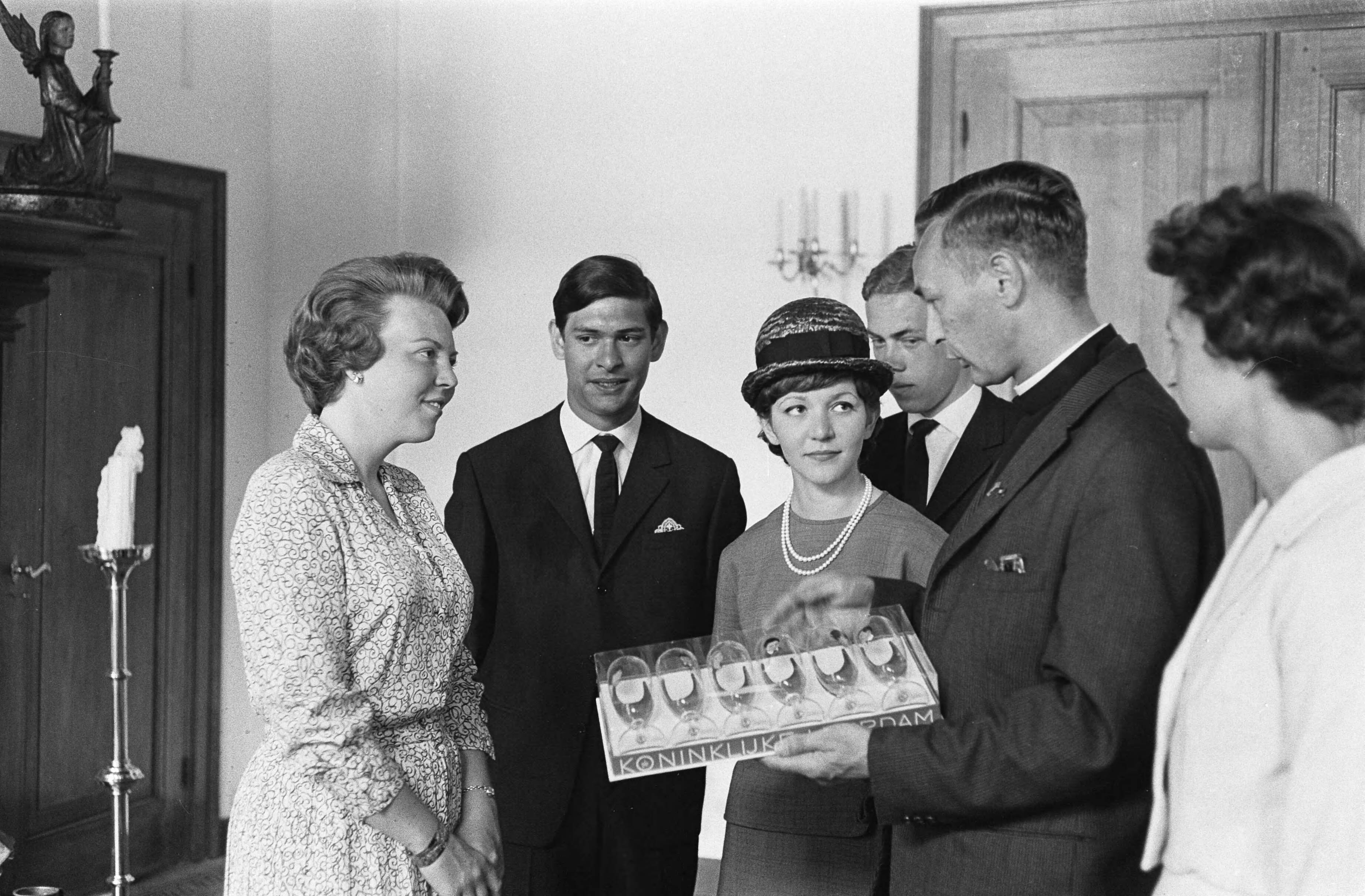 Fotocollectie Anefo — Prinses Beatrix heeft op Kasteel Drakensteyn het actie-comité "Dousadsj" ontvangen, v.l.n.r. Prinses Beatrix , dhr. Rompius, Miss Dousadsj [Adele Rompius-Sadrille], P. van Bueren, pater Werenfried Stokman en mevrouw J. Rigby (penningmeester Europese werkgroep),. Pater Stokman biedt de prinses een set glazen aan met de gegraveerde portretten van Nederlandse artiesten, vervaardigd door Koninklijke Leerdam — Foto: Pot, Harry / Anefo. Licentie: Set B: Rechtenvrij / Publiek Domein. Bron: Nationaal Archief. http://hdl.handle.net/10648/aa3935a2-d0b4-102d-bcf8-003048976d84