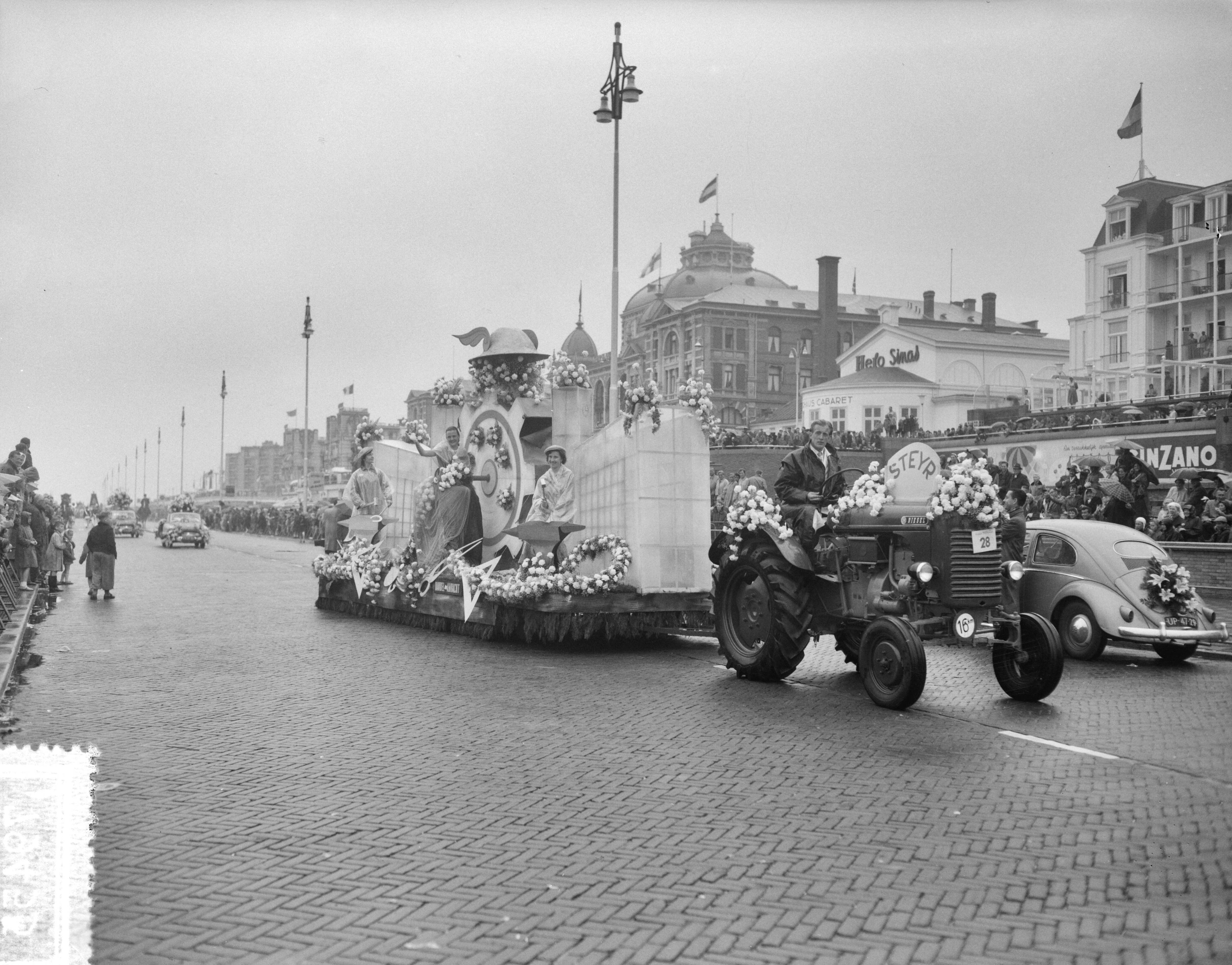 Fotocollectie Anefo — Bloemencorso op de boulevard van Scheveningen. Praalwagen met industriëel thema — Foto: Bilsen, Joop van / Anefo. Licentie: Set B: Rechtenvrij / Publiek Domein. Bron: Nationaal Archief. http://hdl.handle.net/10648/a94d4a52-d0b4-102d-bcf8-003048976d84