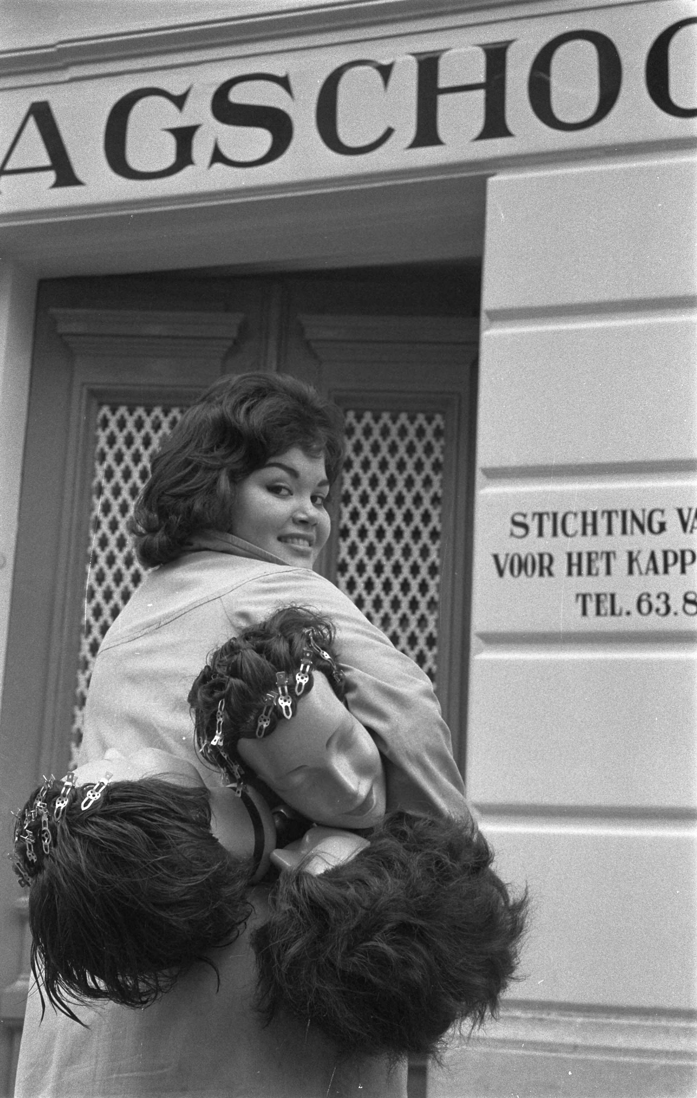Fotocollectie Anefo — Opening van de eerste kappersdagschool aan de Prinses Marijkestraat te Den Haag , een der leerlingen gaat met een paar modellen naar binnen — Foto: Pot, Harry / Anefo. Licentie: Set B: Rechtenvrij / Publiek Domein. Bron: Nationaal Archief. http://hdl.handle.net/10648/a9a90d74-d0b4-102d-bcf8-003048976d84