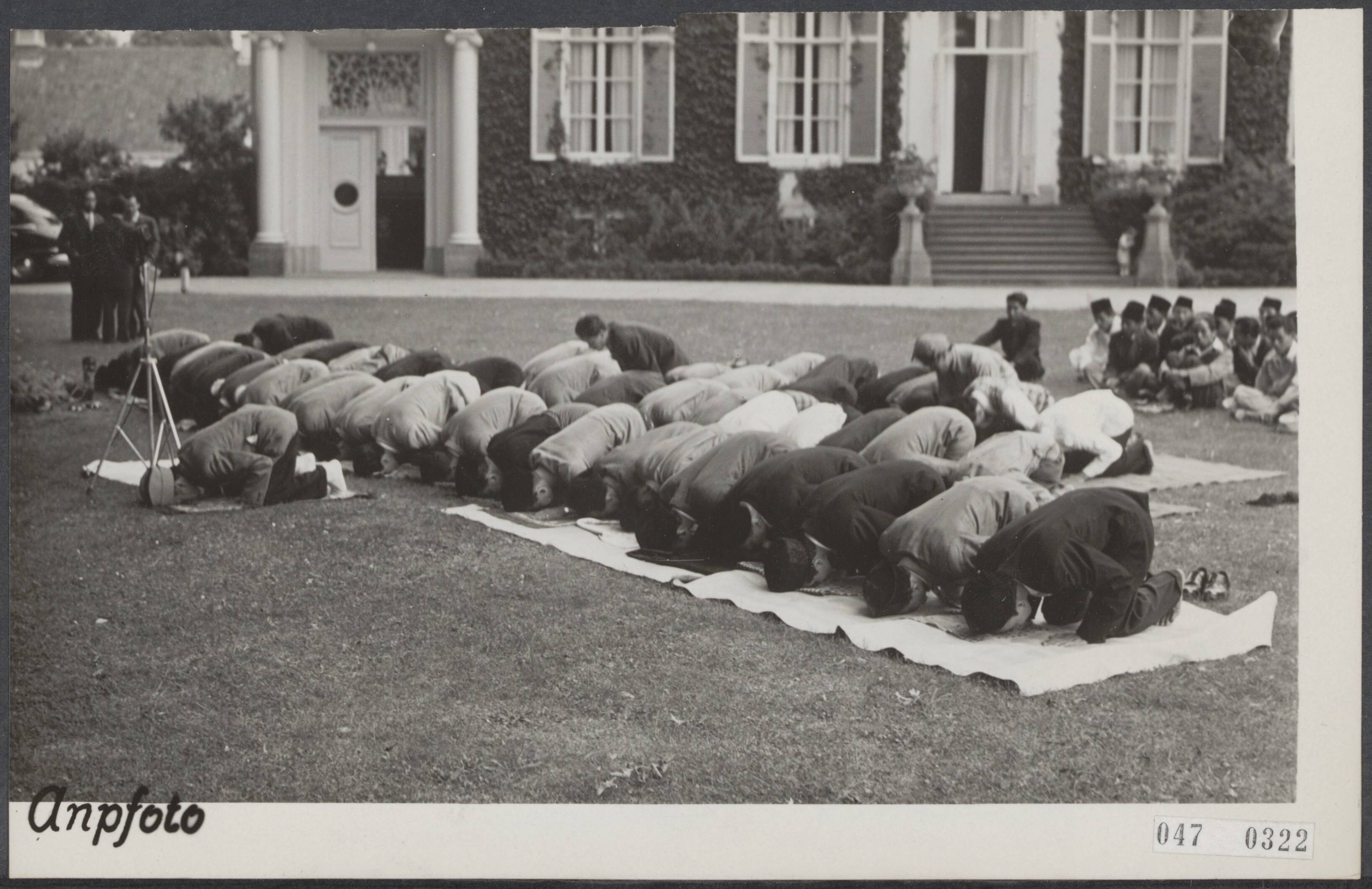 Fotocollectie Elsevier Binnenland — Ter gelegenheid van het einde van de Islamitische vastenmaand (Id ul Fitr, Ramadan0 werd in de tuin van het landgoed Backershagen te Wassenaar, de woning van de Hoge Commissaris van Indonesië, Mohammed Roem, een godsdienstige plechtigheid gehouden. Tijdens het gebed, volgens gebruik liggen allen met hun gezicht naar het Oosten (Mekka) gekeerd — Foto: ANP / RVD of rechtenvrij. Licentie: Set B: Rechtenvrij / Publiek Domein. Bron: Nationaal Archief. http://hdl.handle.net/10648/adff638c-d0b4-102d-bcf8-003048976d84