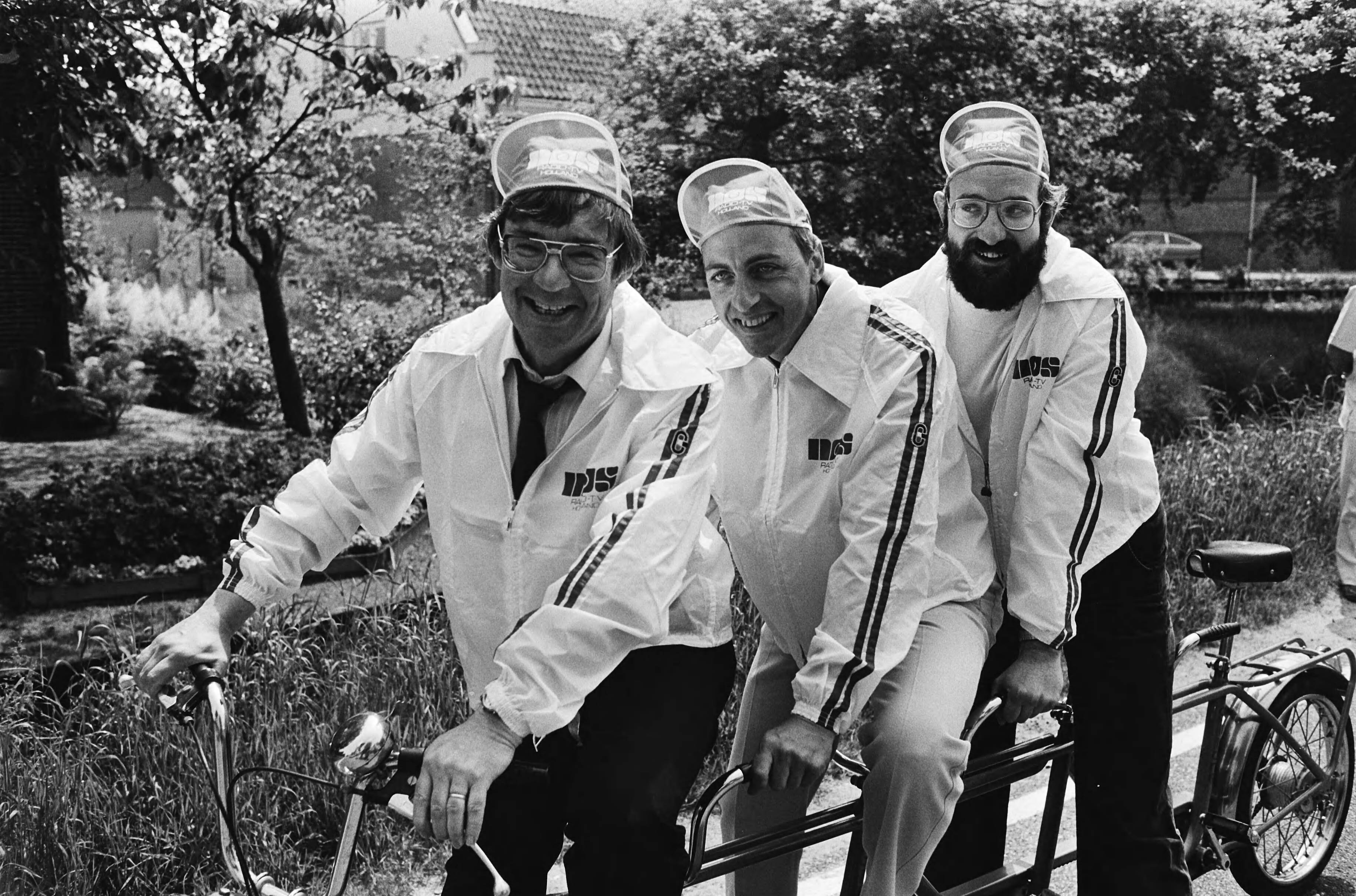 Presentatie van de NOS equipe voor de Tour de France 1979 — Theo Koomen, Heinze Bakker en Hans Prakke — Foto: Suyk, Koen / Anefo. Licentie: Set B: Rechtenvrij / Publiek Domein. Bron: Nationaal Archief. http://hdl.handle.net/10648/accc2478-d0b4-102d-bcf8-003048976d84