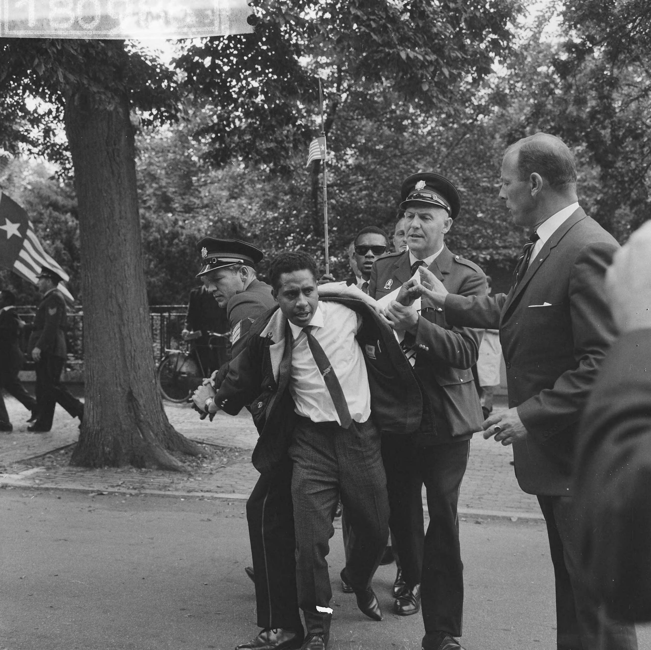 Fotocollectie Anefo — Papoea's demonstreren in Den Haag, een betoger wordt in bedwang gehouden door politieagenten — Foto: Evers, Joost / Anefo. Licentie: Set B: Rechtenvrij / Publiek Domein. Bron: Nationaal Archief. http://hdl.handle.net/10648/aabc6288-d0b4-102d-bcf8-003048976d84