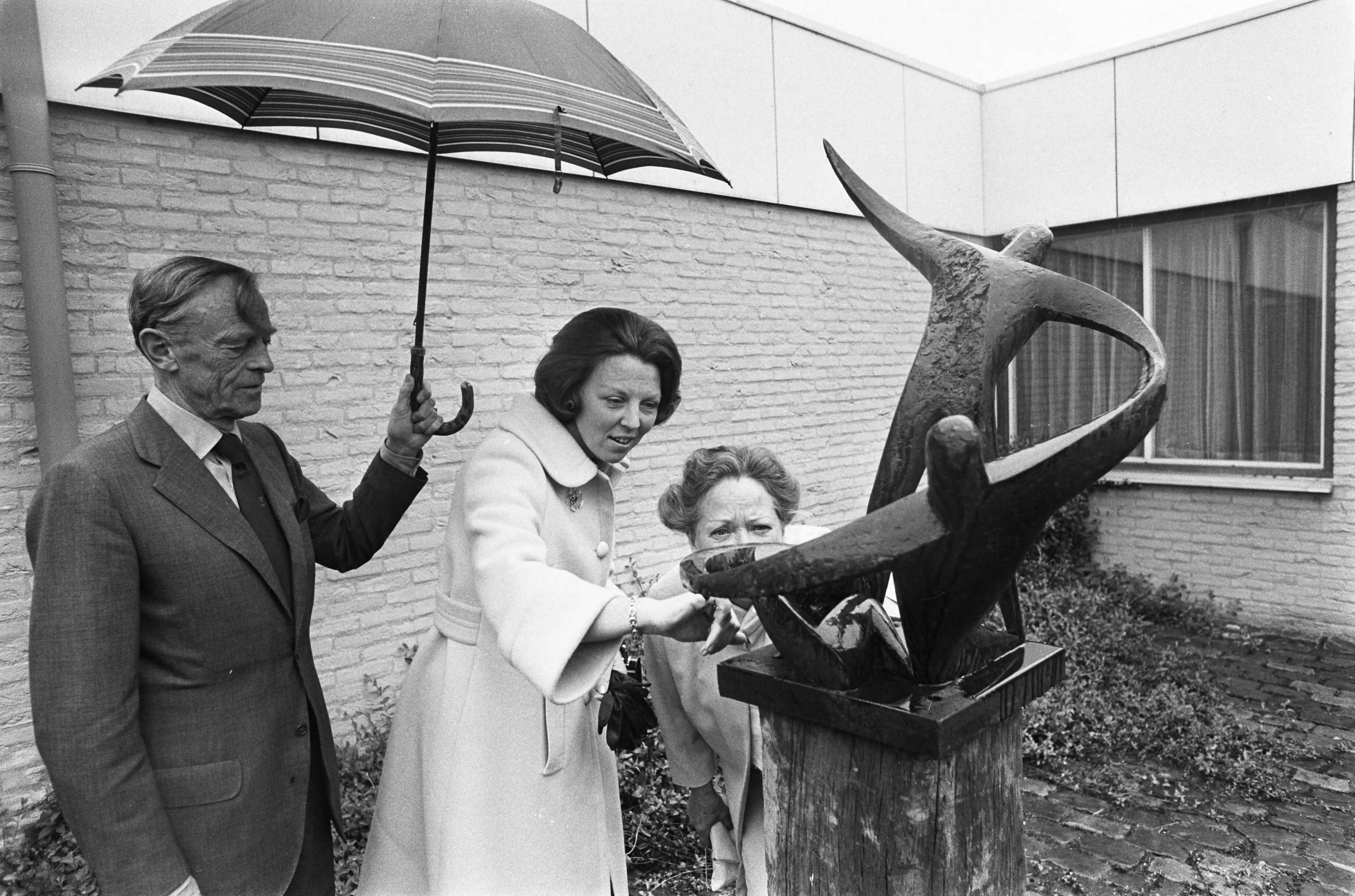 Prinses Beatrix bekijkt haar eigen beeldje in 'Centrum '45' in Oegstgeest — Prinses Beatrix bij haar beeldje, links Hans Teengs Gerritsen [1907-1990] — Foto: Mieremet, Rob / Anefo. Licentie: Set B: Rechtenvrij / Publiek Domein. Bron: Nationaal Archief. http://hdl.handle.net/10648/ac67cdf2-d0b4-102d-bcf8-003048976d84