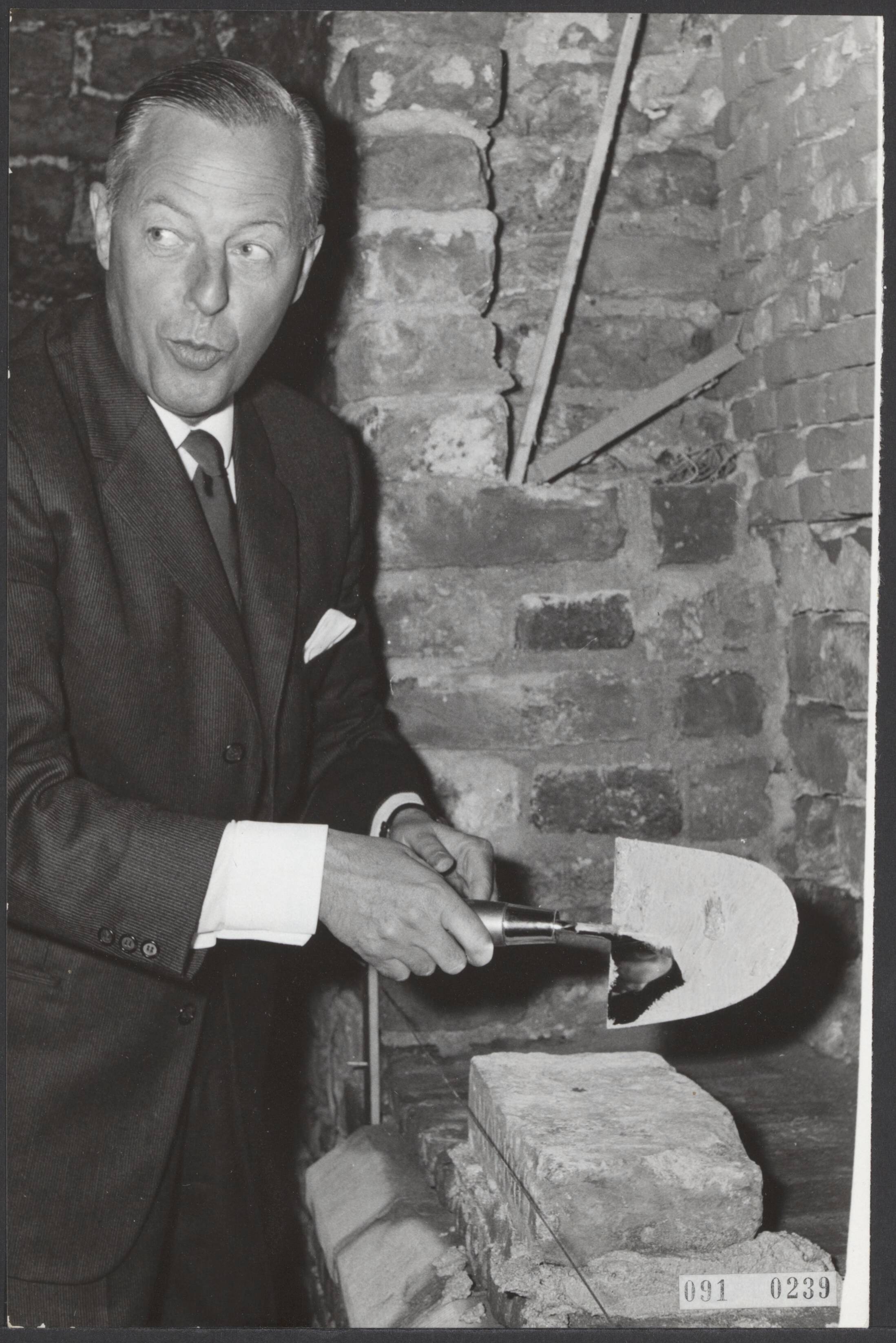 Fotocollectie Elsevier Binnenland — Jhr. Mr. A. Feith, burgemeester van Voorburg, metselde een steen in de Oude Kerk te Voorburg. Het was het sein om met de restauratie van de Hervormde dorpskerk, die dateert uit de 15e eeuw, te beginnen. — Foto: Fotograaf Onbekend / Anefo. Licentie: Set B: Rechtenvrij / Publiek Domein. Bron: Nationaal Archief. http://hdl.handle.net/10648/ae1f6416-d0b4-102d-bcf8-003048976d84