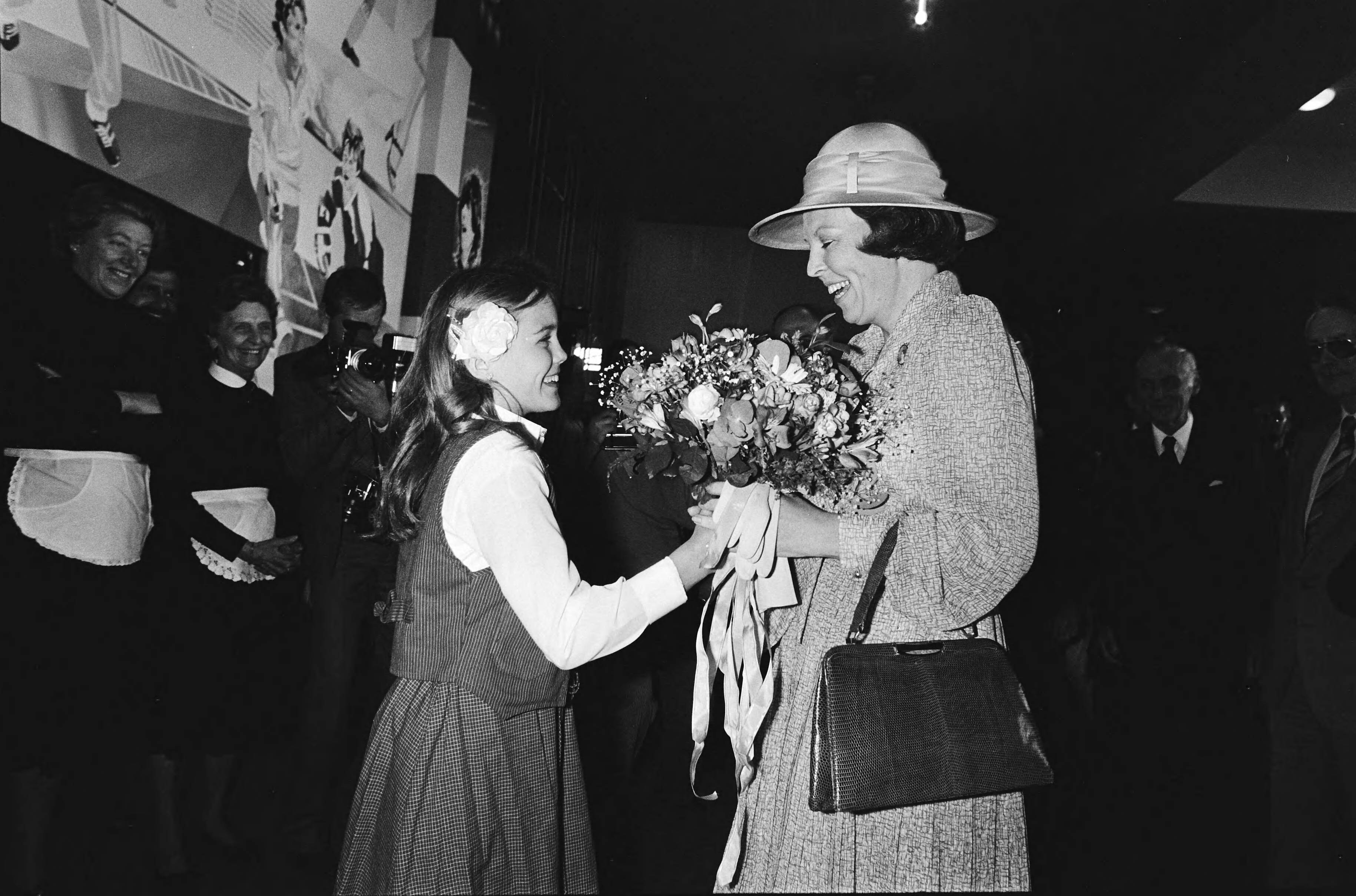 Fotocollectie Anefo — Koninklijke Familie woont bevrijdingsmanifestatie bij in Houtrusthallen in Den Haag ; aanbieden van bloemen — Foto: Suyk, Koen / Anefo. Licentie: Set B: Rechtenvrij / Publiek Domein. Bron: Nationaal Archief. http://hdl.handle.net/10648/acdfecba-d0b4-102d-bcf8-003048976d84