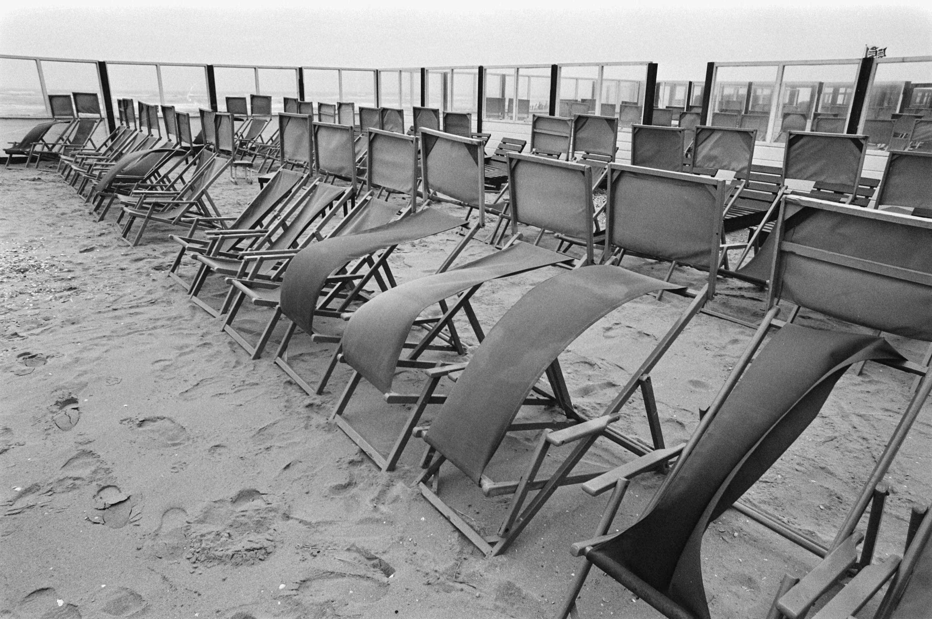 Fotocollectie Anefo — Slecht weer met pasen; harde wind heeft vrij spel op onbezette strandstoelen — Foto: Bogaerts, Rob / Anefo. Licentie: Set B: Rechtenvrij / Publiek Domein. Bron: Nationaal Archief. http://hdl.handle.net/10648/ad451856-d0b4-102d-bcf8-003048976d84