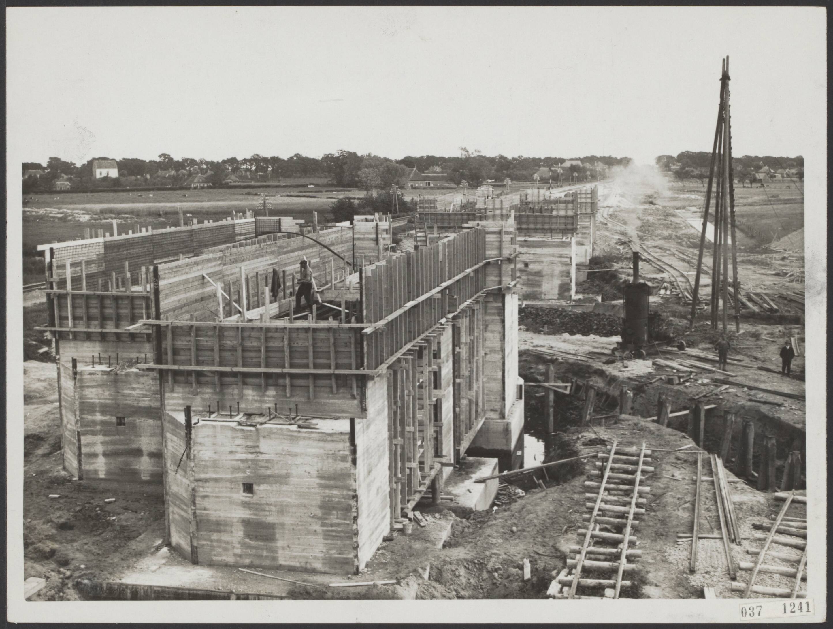 Fotocollectie Elsevier Binnenland — Overzicht van de werkzaamheden voor de spoorbrug waarover de lijn Groningen-Leeuwarden zal lopen, als het kanaal Groningen-Zuidhorn gereed zal zijn gekomen. De pijlers in vogelvlucht — Foto: N.V. Polygoon. Licentie: Set B: Rechtenvrij / Publiek Domein. Bron: Nationaal Archief. http://hdl.handle.net/10648/adeff230-d0b4-102d-bcf8-003048976d84