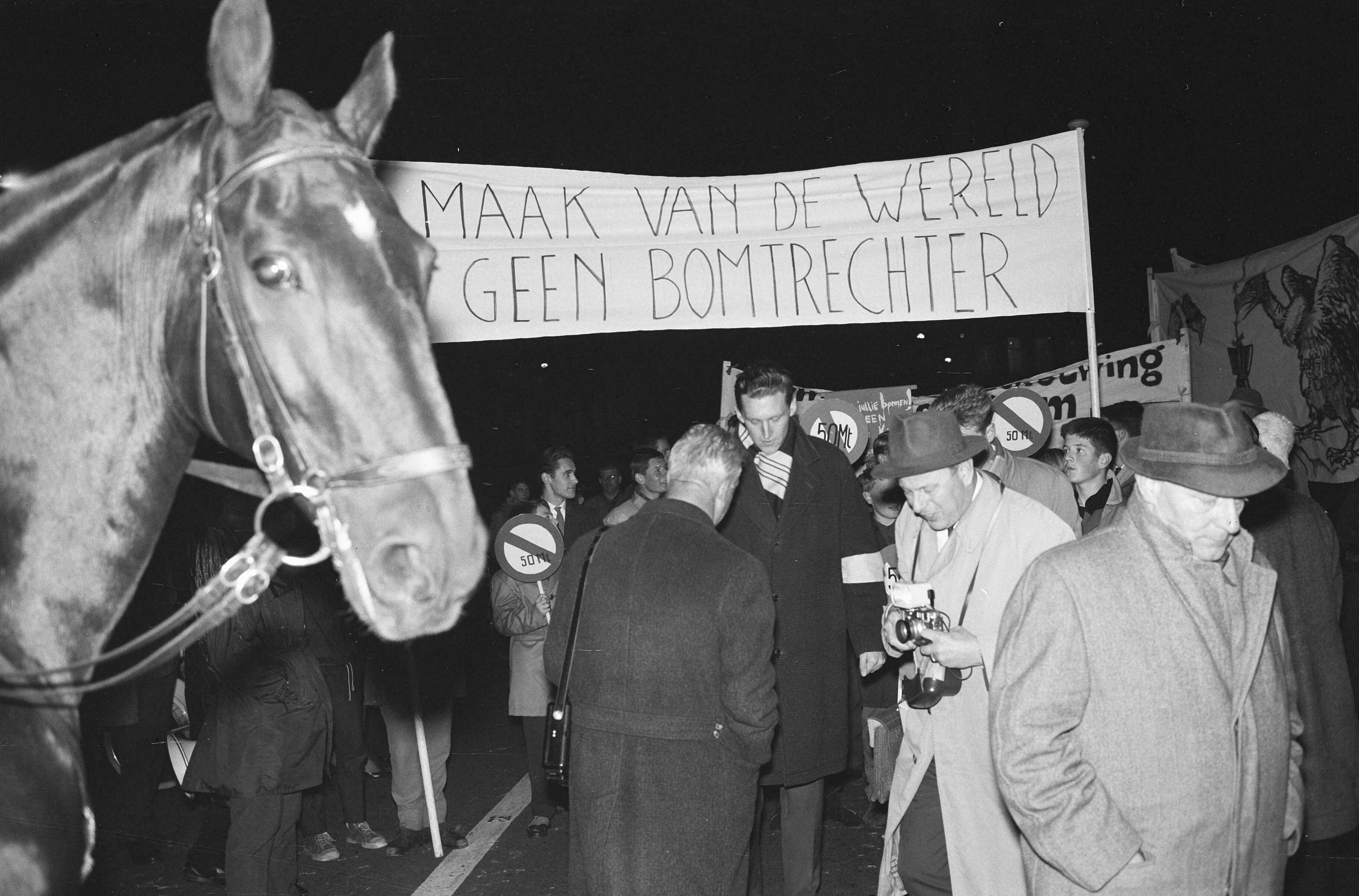 Fotocollectie Anefo — Betogers met spandoeken tijdens een anti-atoombomdemonstratie in Den Haag — Foto: Boer, […] de / Anefo. Licentie: Set B: Rechtenvrij / Publiek Domein. Bron: Nationaal Archief. http://hdl.handle.net/10648/a9e99916-d0b4-102d-bcf8-003048976d84