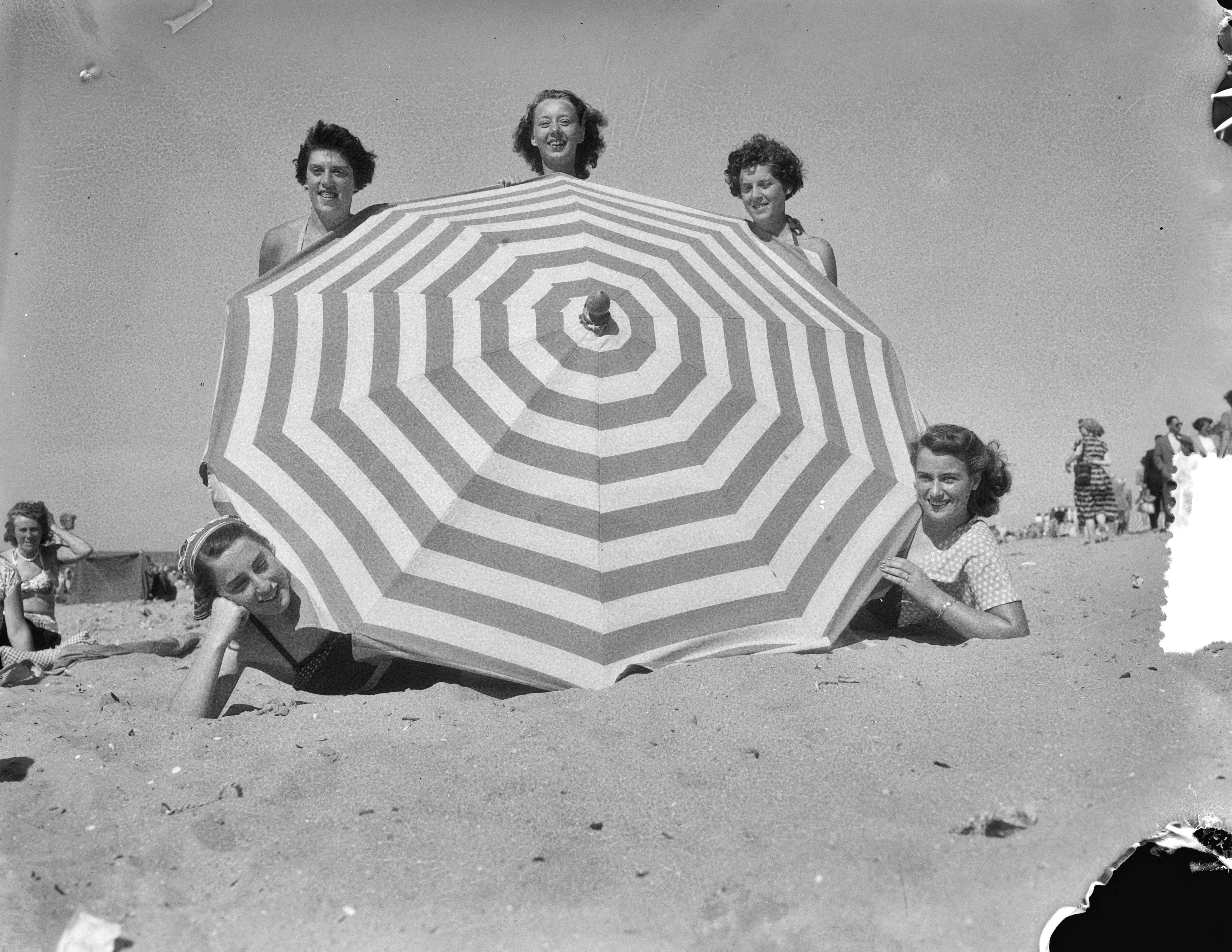 Fotocollectie Anefo — Strandplaatjes Scheveningen. Parasol en badschonen — Foto: Consenheim, Wim / Anefo. Licentie: Set B: Rechtenvrij / Publiek Domein. Bron: Nationaal Archief. http://hdl.handle.net/10648/a8fe4e66-d0b4-102d-bcf8-003048976d84