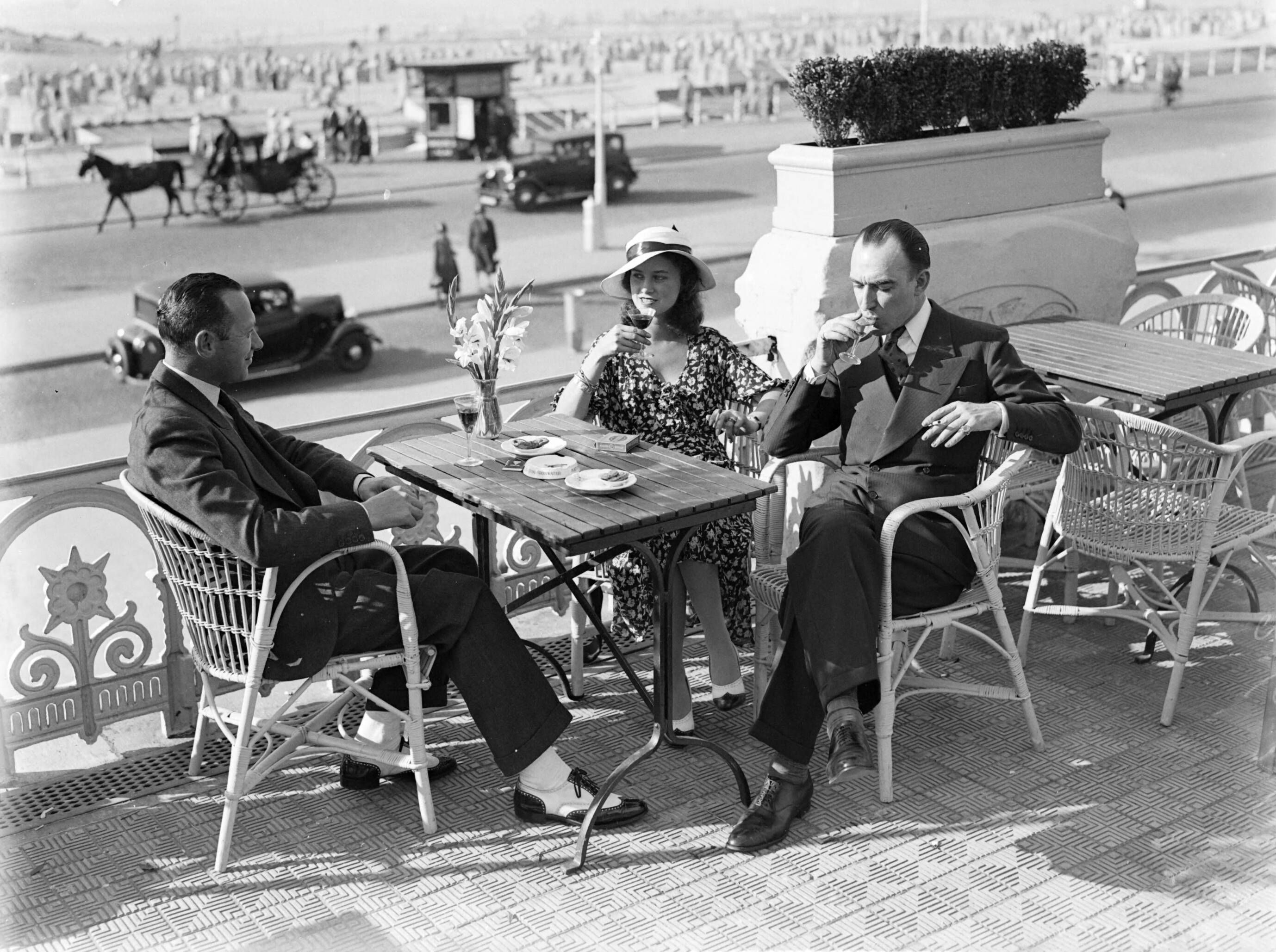 Scheveningen. — Een vrouw (mevrouw Ott?) en twee mannen op een terras aan de boulevard in Scheveningen — Foto: Poll, Willem van de. Licentie: Set B: Rechtenvrij / Publiek Domein. Bron: Nationaal Archief. http://hdl.handle.net/10648/ae9ab3c8-d0b4-102d-bcf8-003048976d84