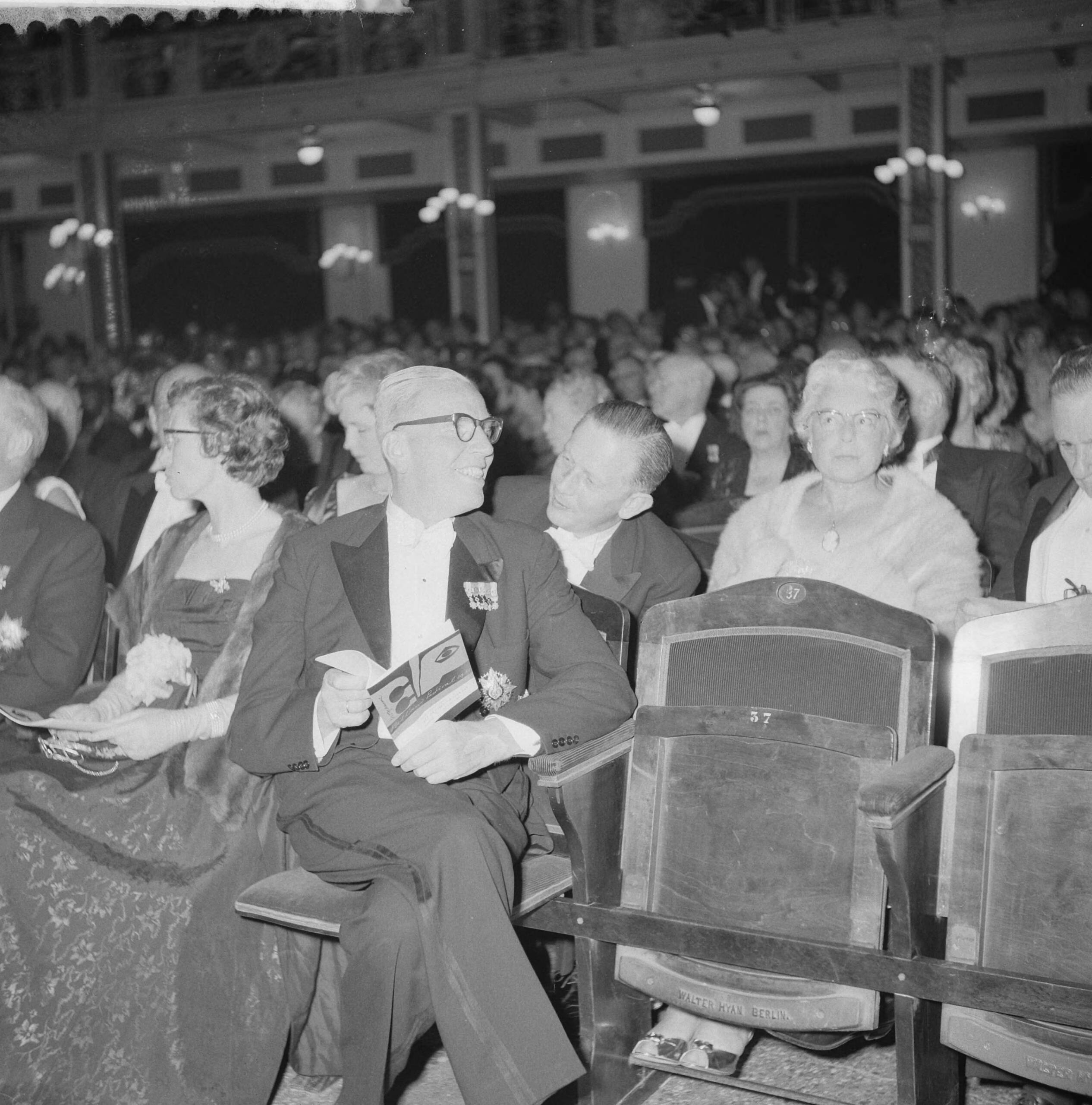 Opening Holland Festival 1961 in het Kurhaus — Opening Holland Festival 1961 in het Kurhaus te Scheveningen. Hoge gasten in het publiek. Minister Beerman spreekt met staatssecretaris Y. Scholten — Foto: Lindeboom, Henk / Anefo. Licentie: Set B: Rechtenvrij / Publiek Domein. Bron: Nationaal Archief. http://hdl.handle.net/10648/a9d8c604-d0b4-102d-bcf8-003048976d84