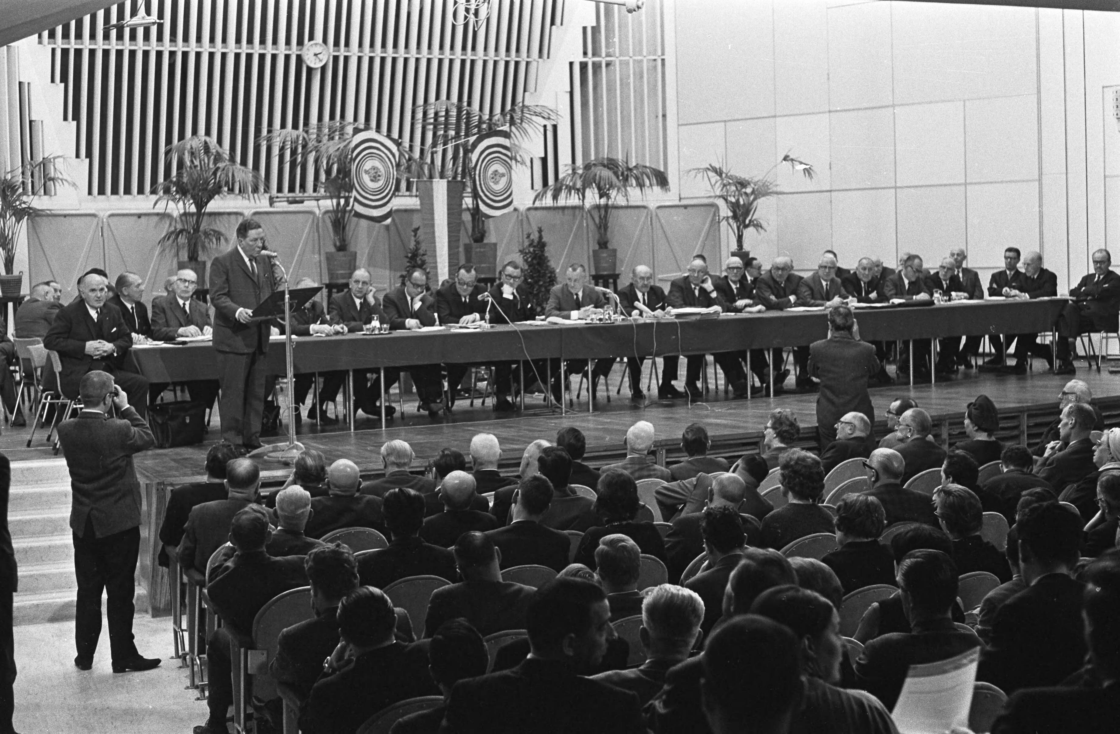 Fotocollectie Anefo — Buitengewone Algemene Vergadering van de AVRO in Hilversum, overzicht tijdens toespraak van oud-voorzitter Willem Vogt — Foto: Merk, Ben / Anefo. Licentie: Set B: Rechtenvrij / Publiek Domein. Bron: Nationaal Archief. http://hdl.handle.net/10648/ab0f2d88-d0b4-102d-bcf8-003048976d84