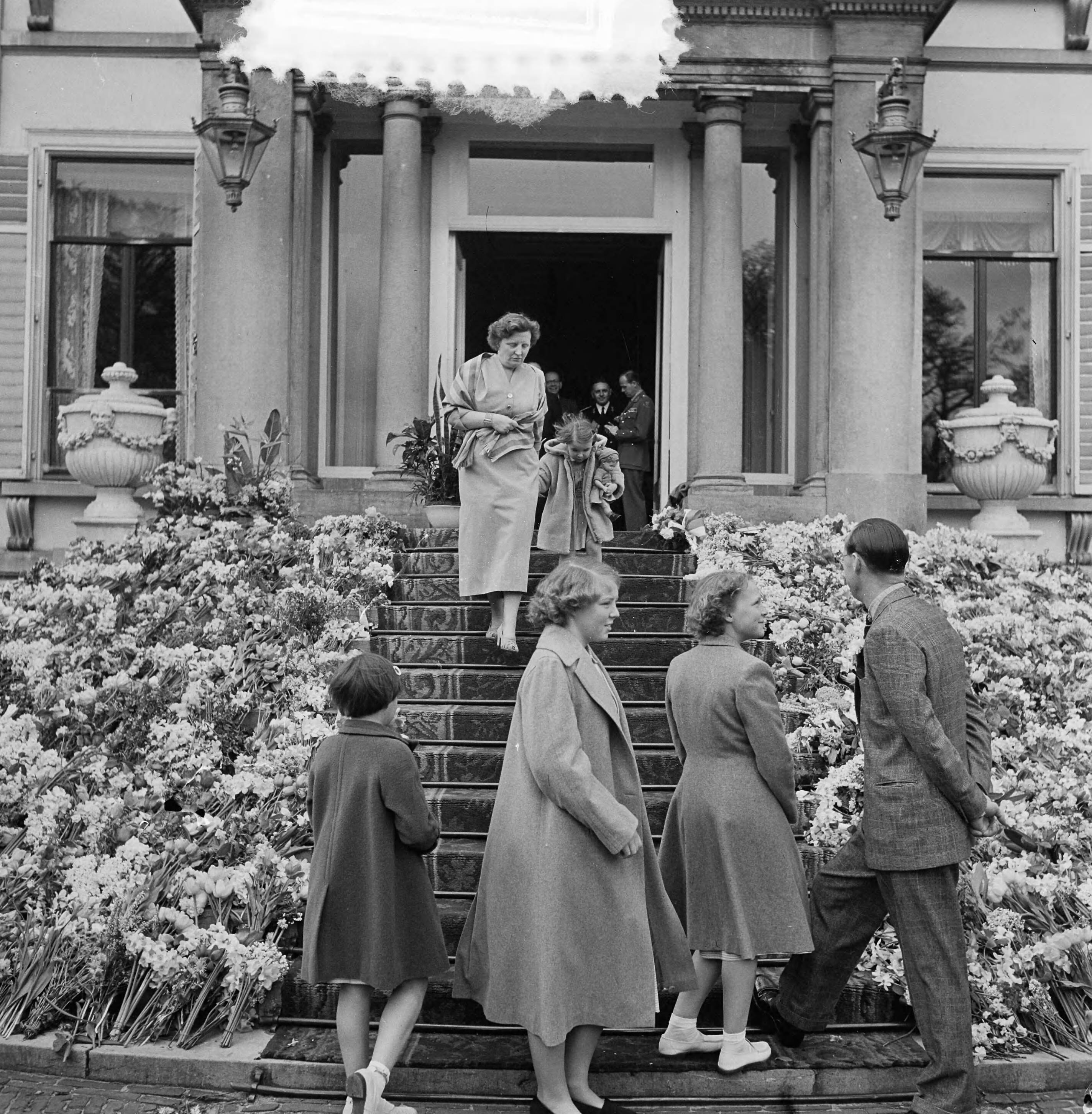 Koninginnedag 1953 — Koninklijk gezin kijkt naar de voorbij trekkende delegatie. Weggelopen Marijke werd door haar moeder teruggebracht — Foto: Noske, J.D. / Anefo. Licentie: Set B: Rechtenvrij / Publiek Domein. Bron: Nationaal Archief. http://hdl.handle.net/10648/a90b408a-d0b4-102d-bcf8-003048976d84