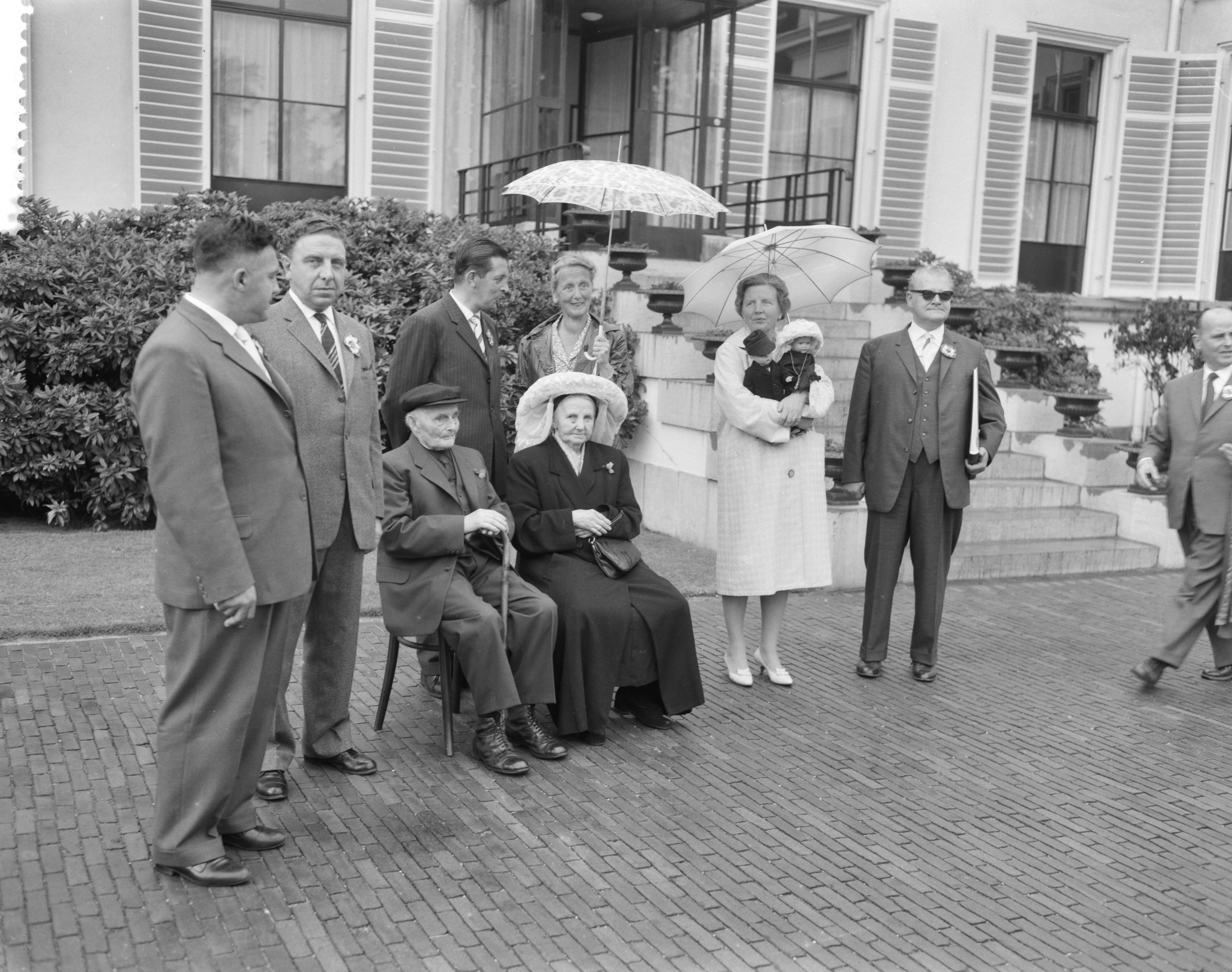 Fotocollectie Anefo — Defilé van ouden van dagen op Soestdijk. Koningin Juliana krijgt poppen, links echtpaar Voges — Foto: Behrens, Herbert F. / Anefo. Licentie: Set B: Rechtenvrij / Publiek Domein. Bron: Nationaal Archief. http://hdl.handle.net/10648/a9b387a4-d0b4-102d-bcf8-003048976d84