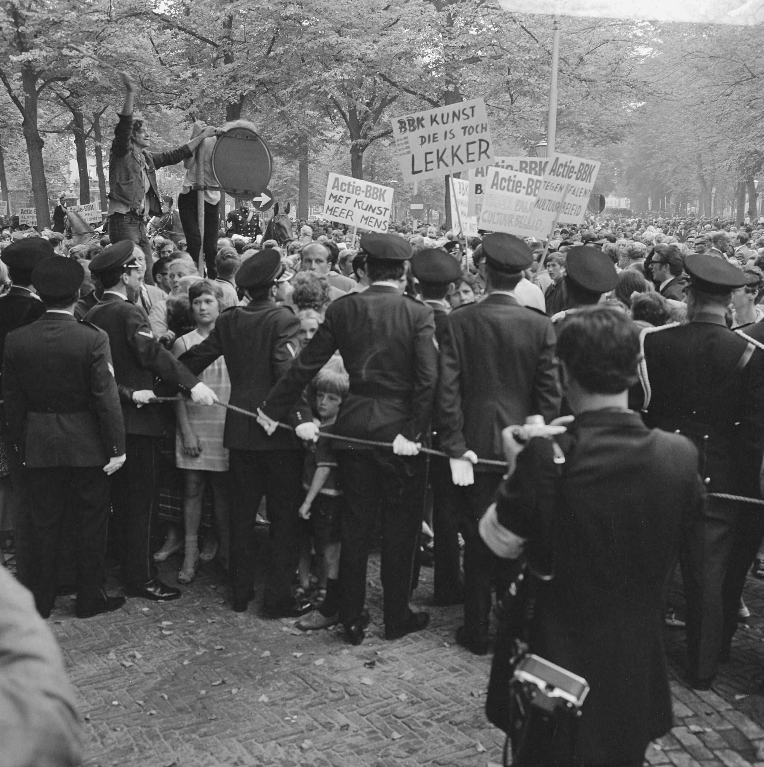 Fotocollectie Anefo — Kunstenaars van de BBK protesteren met borden tegen het cultuurbeleid op Lange Voorhout Den Haag tijdens rit Kon. Fam. naar Pal. Lange Voorhout : demonstrerende — Foto: Koch, Eric / Anefo. Licentie: Set B: Rechtenvrij / Publiek Domein. Bron: Nationaal Archief. http://hdl.handle.net/10648/ab7a041e-d0b4-102d-bcf8-003048976d84