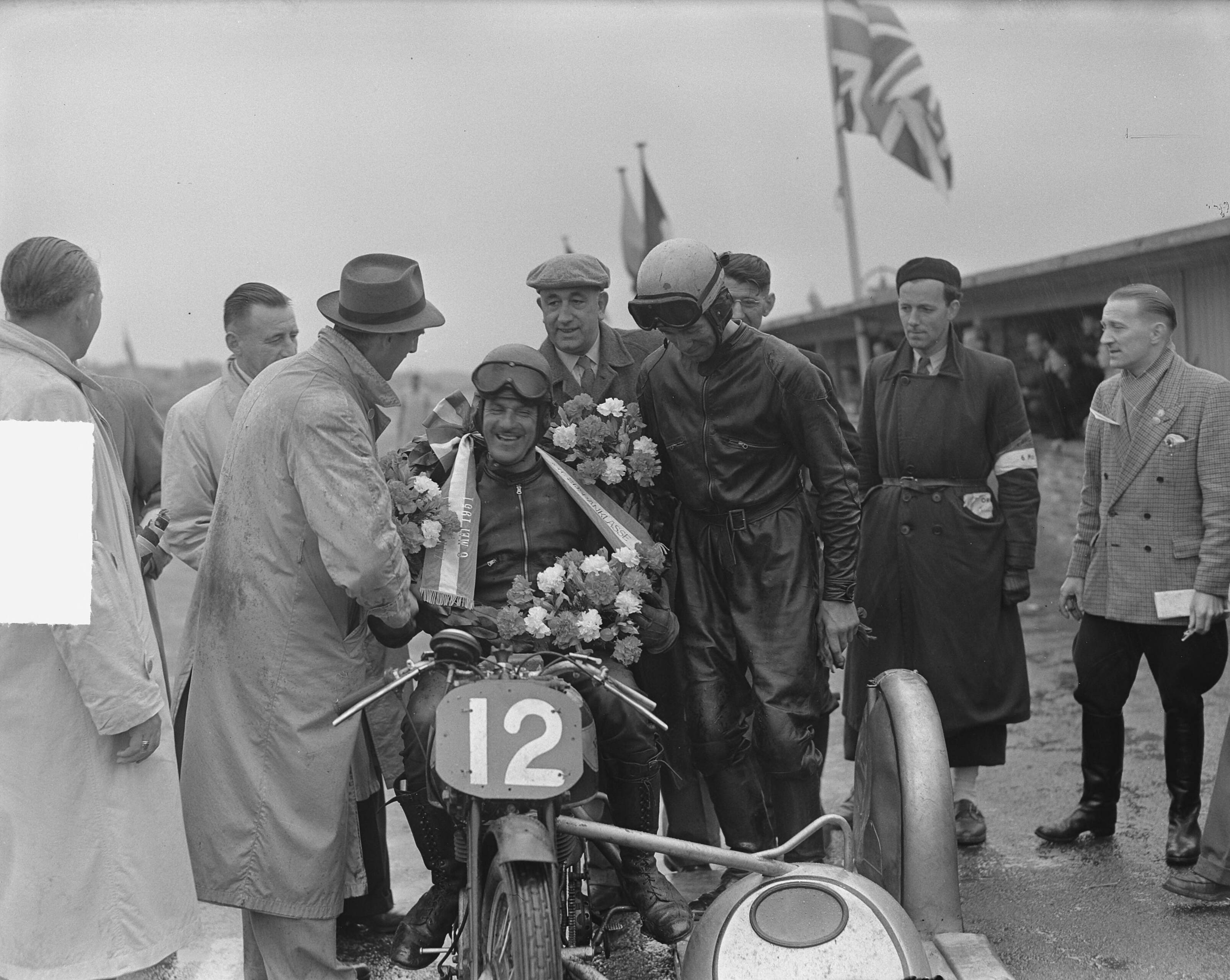 Fotocollectie Anefo — Internationale Motorraces te Zandvoort. Winnaar zijspanklasse, de Engelsman Oliver — Foto: Bilsen, Joop van / Anefo. Licentie: Set B: Rechtenvrij / Publiek Domein. Bron: Nationaal Archief. http://hdl.handle.net/10648/a8e9aaba-d0b4-102d-bcf8-003048976d84