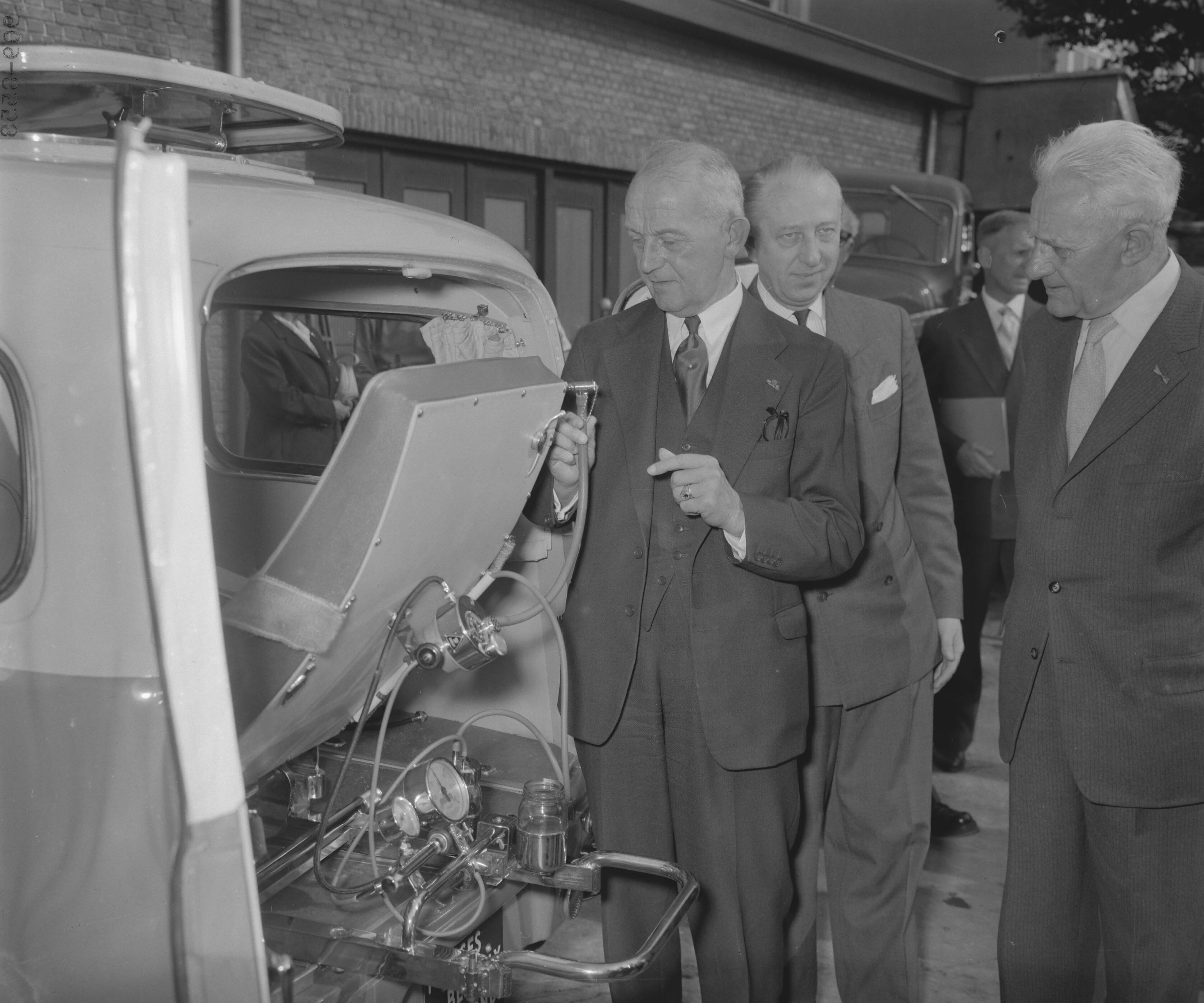 Fotocollectie Anefo — Eerste Nederlandse polio-auto is in een showroom aan de Koninginnegracht te Den Haag aangeboden aan burgemeester Kolfschoten en door hem overgedragen aan de geneesheer-directeur van de Gemeenteziekenhuizen dr. Hulscher. De auto is een geschenk van de bevolking van Den Haag, Scheveningen, Wassenaar en enkele Westlandse gemeenten — Foto: Noske, J.D. / Anefo. Licentie: Set B: Rechtenvrij / Publiek Domein. Bron: Nationaal Archief. http://hdl.handle.net/10648/a984d332-d0b4-102d-bcf8-003048976d84