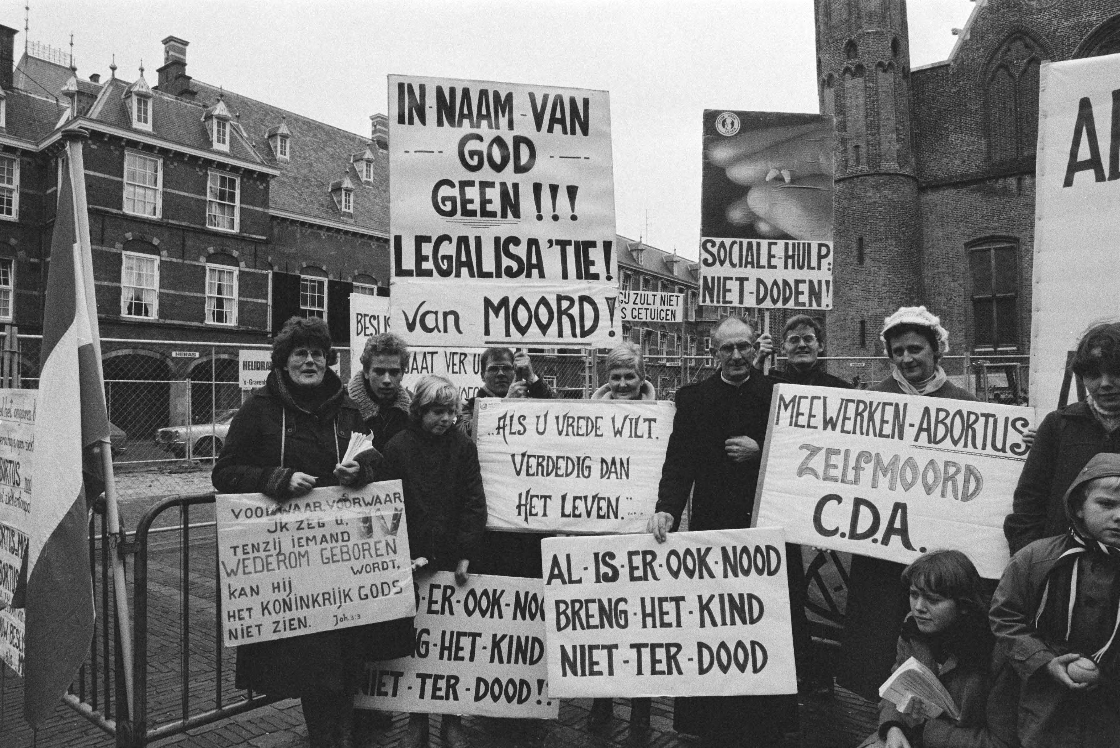 Fotocollectie Anefo — Demonstratie van tegenstanders van abortus op Binnenhof, Den Haag , demonstranten met in midden Pater Koopman — Foto: Dijk, Hans van / Anefo. Licentie: Set B: Rechtenvrij / Publiek Domein. Bron: Nationaal Archief. http://hdl.handle.net/10648/aced9536-d0b4-102d-bcf8-003048976d84